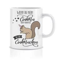 Lade das Bild in den Galerie-Viewer, Ein humorvolles Bild einer Tasse mit dem Schriftzug 'Wenn du kein Einhorn sein kannst, sei ein Einhörnchen' und einem niedlichen Einhörnchen-Motiv. Die Tasse steht auf einem Tisch und strahlt Spaß und Einzigartigkeit aus.